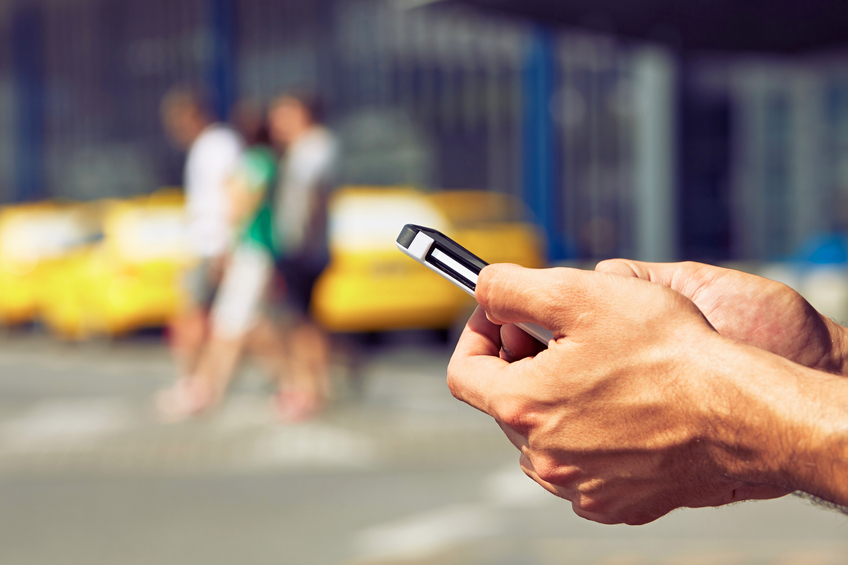 Hands of man ordering taxi, using mobile phone app