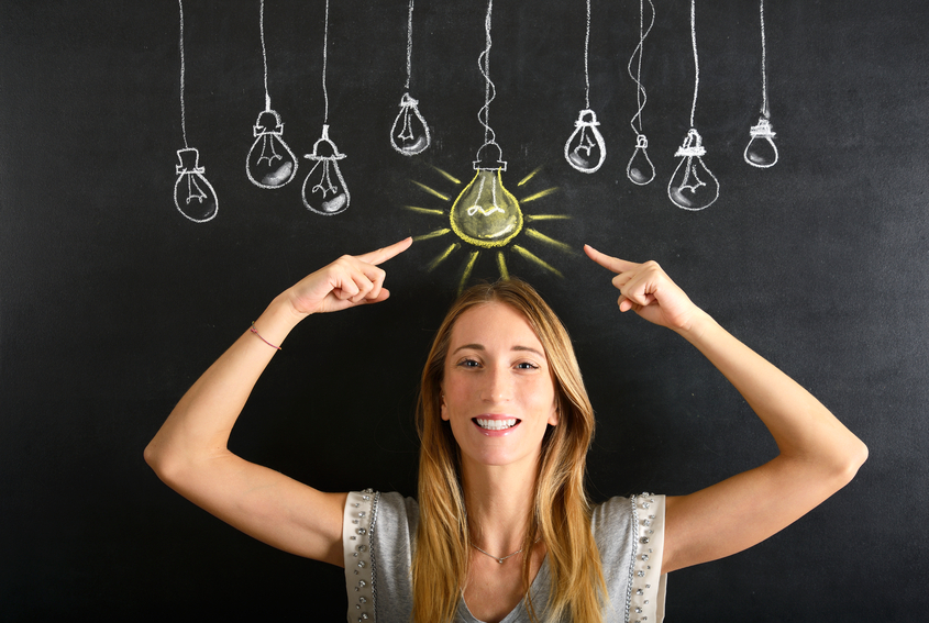 Young businesswoman pointing a big glowing light bulb sketched on blackboard